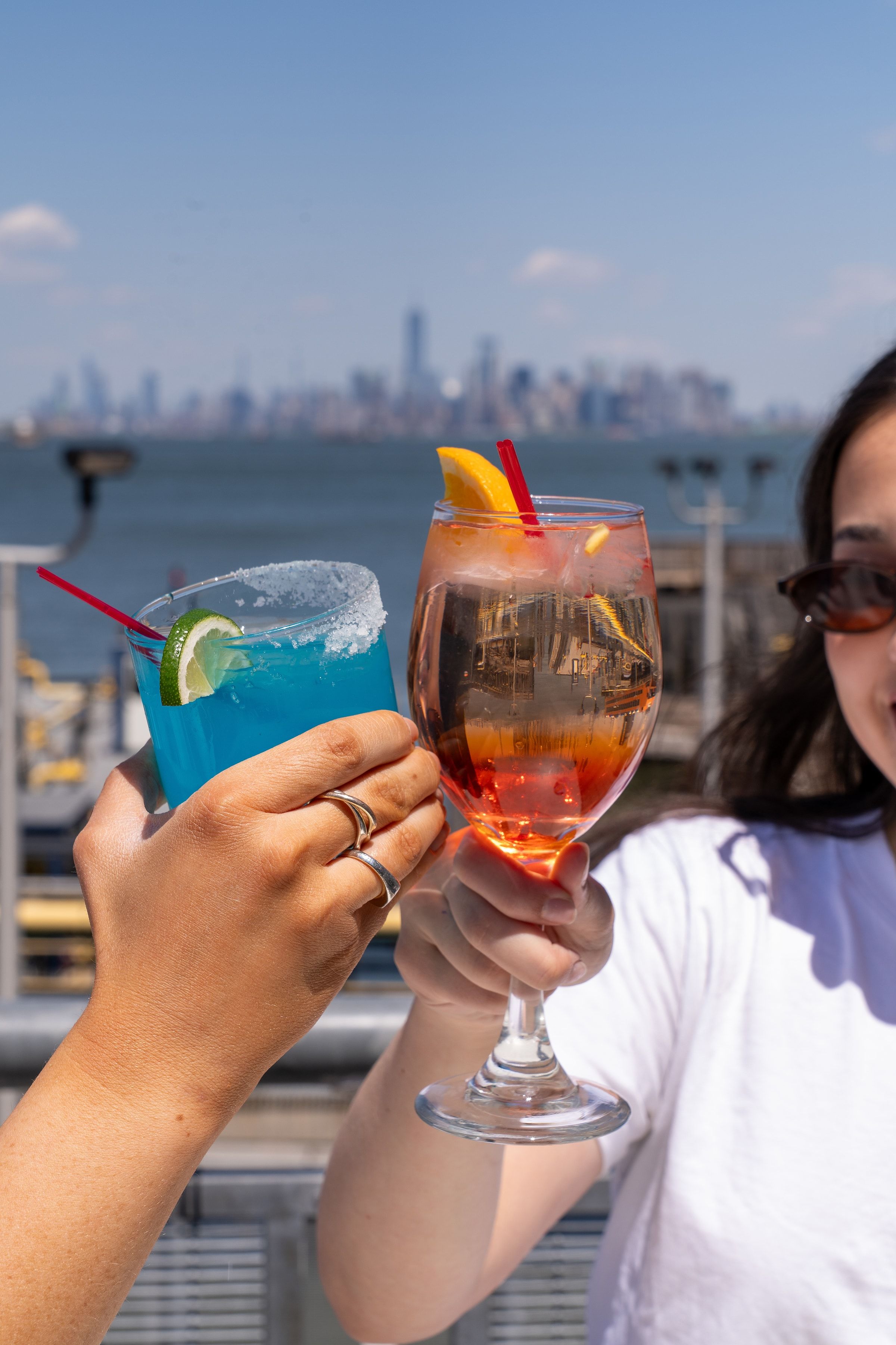Two cocktails on a Staten Island waterfront table, the Manhattan skyline beyond